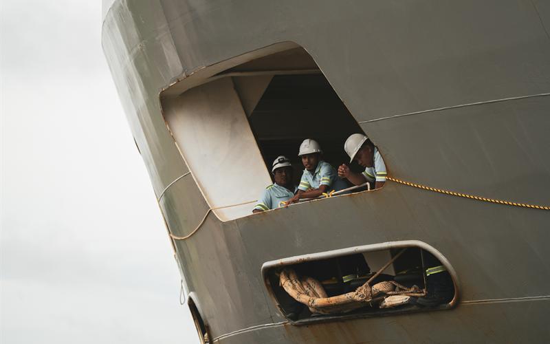 Crew members in hard hats looking out from a ship's bow